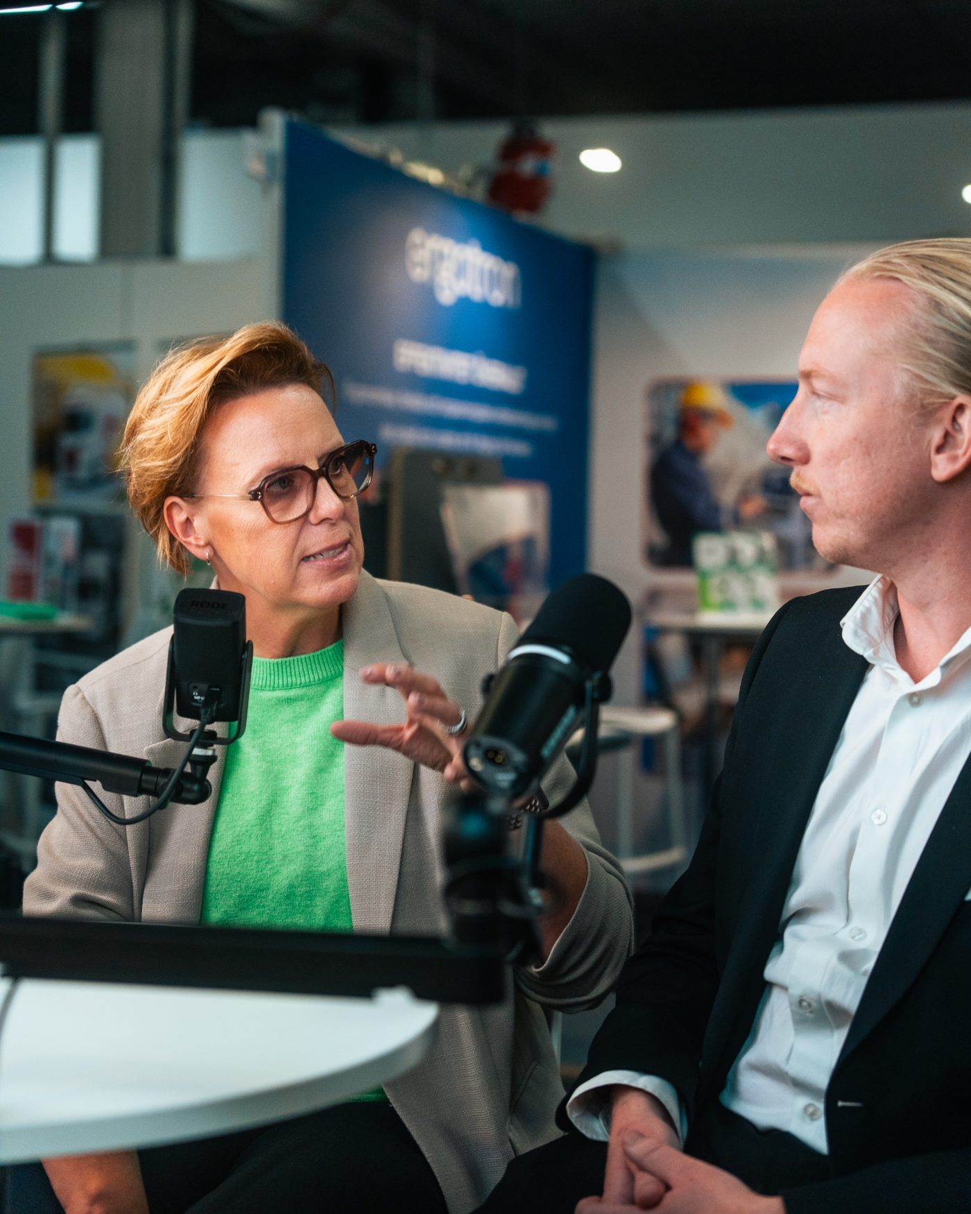 Annsi Krol in close conversation with a guest at a microphone during an event
