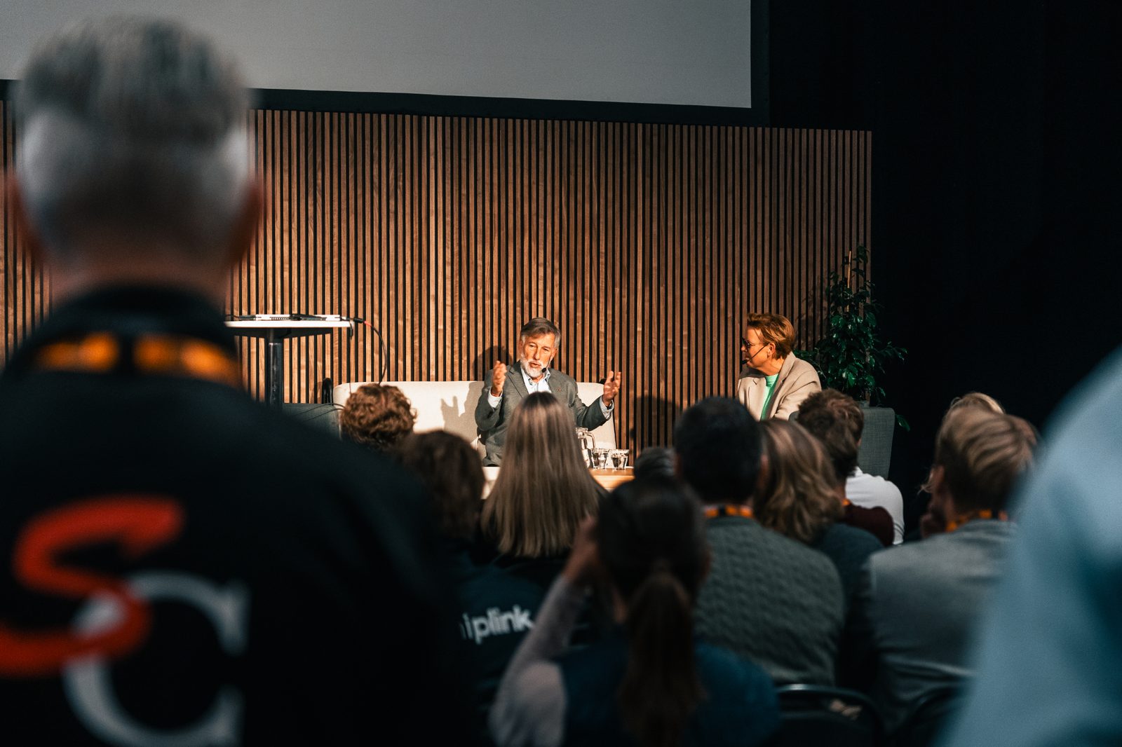 Annsi Krol moderating a stage conversation with a guest speaker in front of an audience