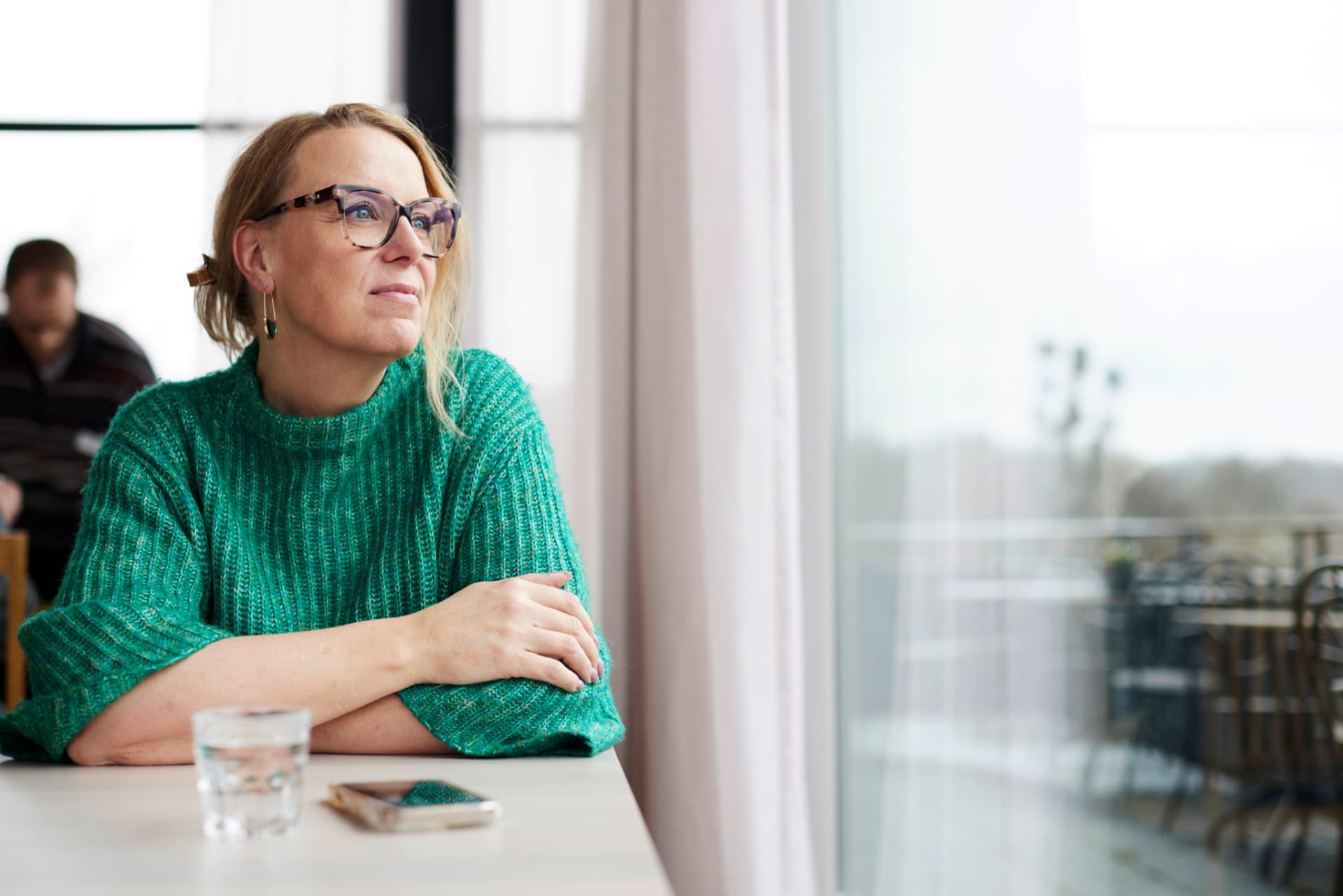 Annsi Krol in an emerald sweater, seated thoughtfully near a window